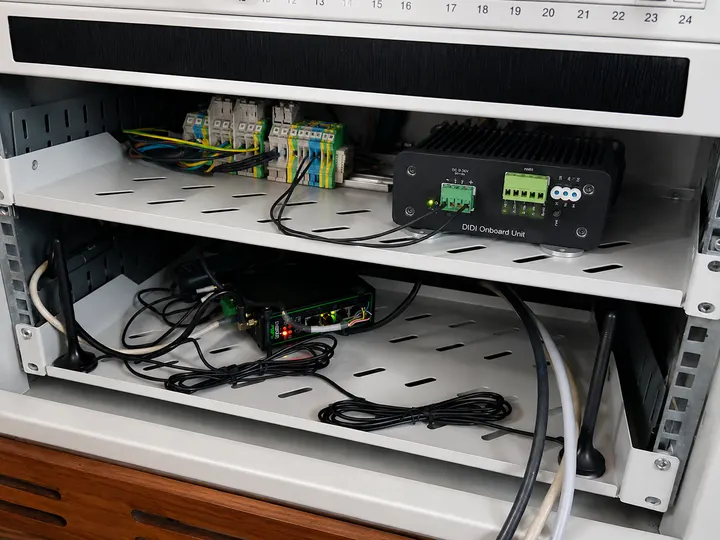 DIDI Onboard Unit on an equipment rack shelf above a cellular router and antennas, wired to terminal blocks